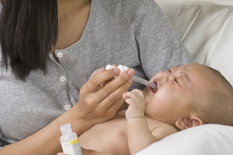 mama asiatică oferind medicamente copilului